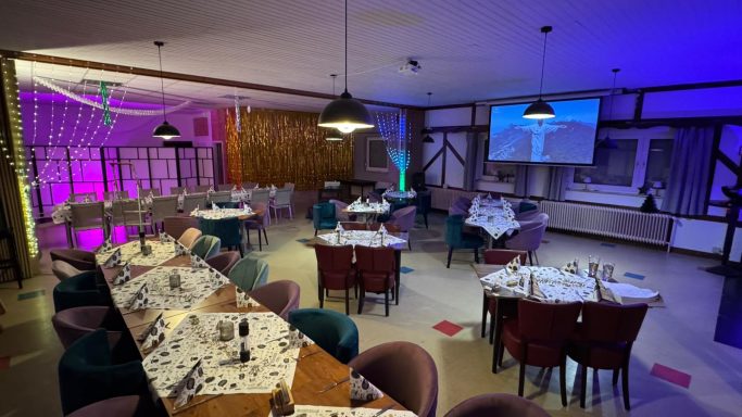 Elegantes Restaurant mit gedeckten Tischen, buntem Licht und modernem Ambiente.