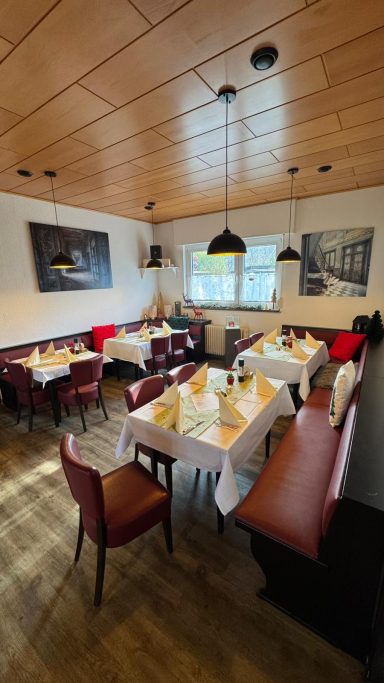 Gemütliches Restaurant mit roten und braunen Sitzgelegenheiten und eingedeckten Tischen.