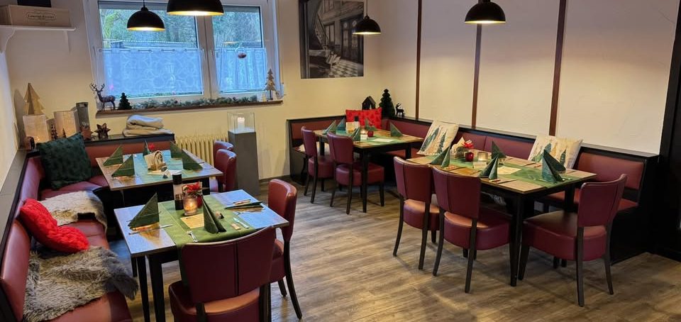 Gemütliches Restaurant mit Tischen, Stühlen und festlicher Tischdekoration.
