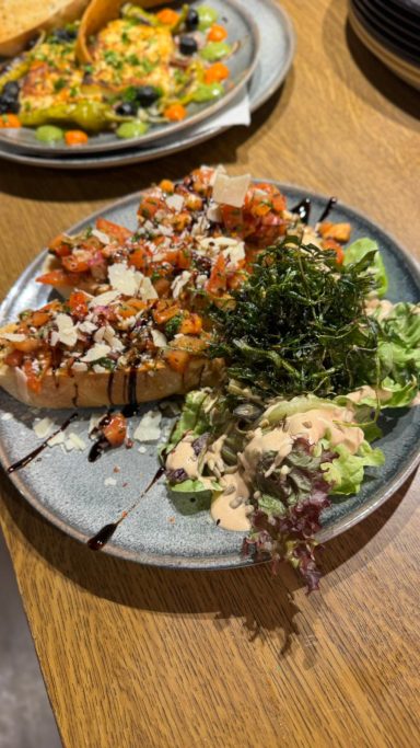 Bruschetta mit frischem Salat und einer cremigen Sauce auf einem Teller.