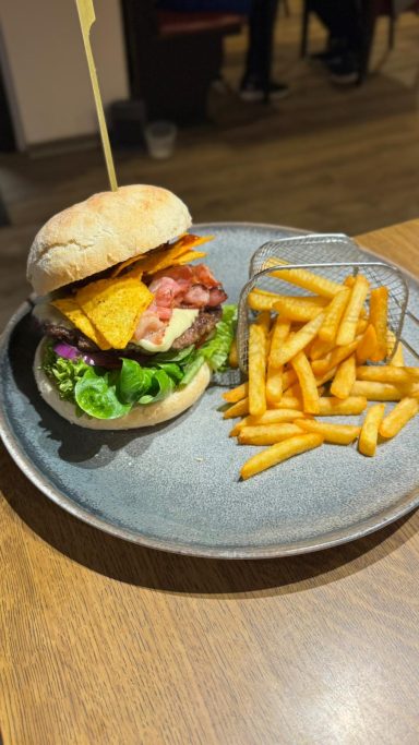 Burger mit Salat und Chips auf einem Teller.